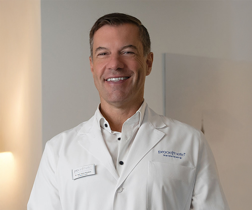 Priv.-Doz. Dr. med. Oliver Kloeters Porträt eines lächelnden Arztes im weißen Kittel bei Proaesthetic